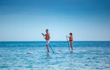 Casal praticando stand up paddle.