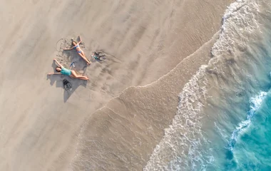Due persone sdraiate su una spiaggia di sabbia finissima con mare cristallino ai Caraibi
