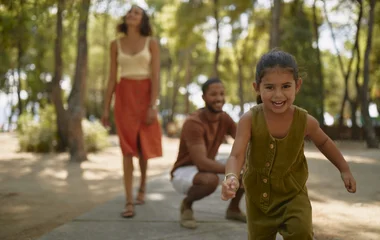 Niña corriendo, con sus padres detrás.