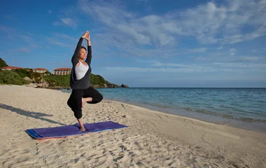Mujer en yoga por la playa.