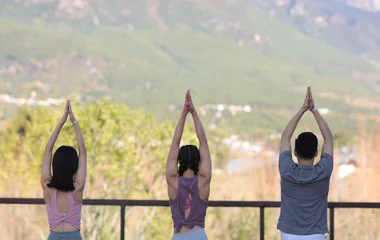 Tres personas practicando yoga frente a la montaña.