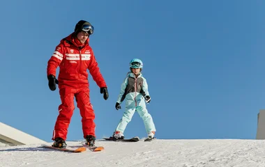Niño aprendiendo a esquiar con un instructor.