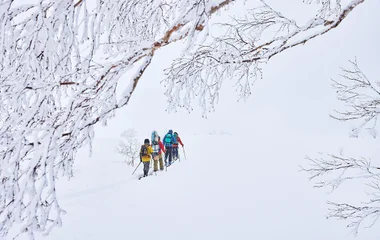 Vista panorâmica das montanhas nevadas de Hokkaido com pessoas caminhando de raquete ao fundo