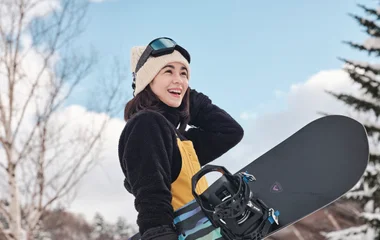 Menina feliz praticando snowboard.