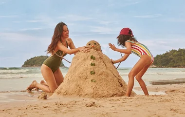 Mãe e filha na areia da praia