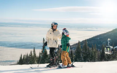 Mãe e filho em um cenário de neve com trajes de esqui.