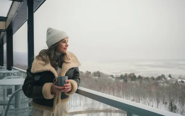 mulher olhando para a neve na varanda