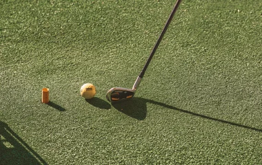 Imagem de perto do taco e bola de golfe.