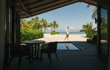 Hombre caminando en villa Exclusive Collection con piscina.