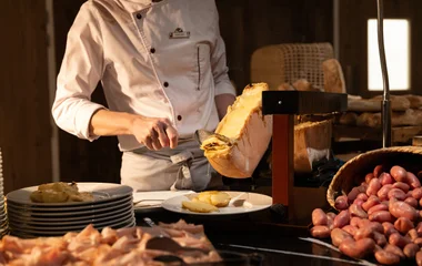Chef em estação de comida adicionando queijo à um prato