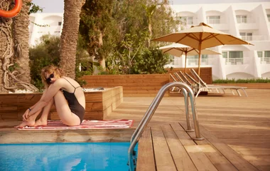 Mujer sentada cerca de la piscina en un resort.