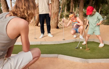 Adultos e crianças se divertindo enquanto praticam golfe