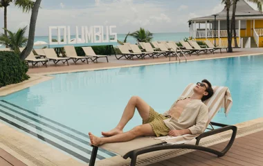 Hombre tumbado en una reposera cerca de la piscina.