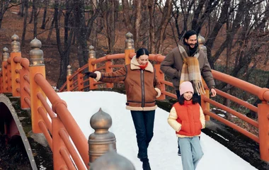 família de homem mulher e criança atravessando ponte nevada