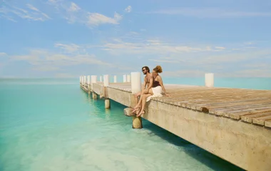 Casal sentado no pier do resort.