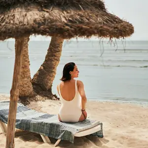 mujer sentada en la reposera con mar de fondo