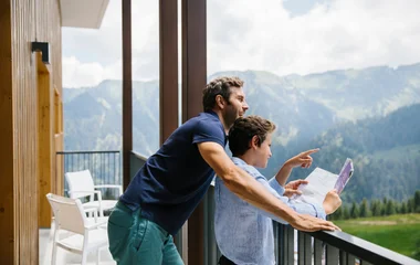 Casal observando as montanhas da sacada do quarto.