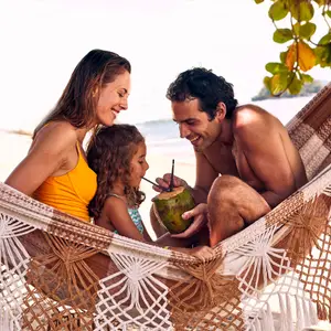 Mãe, pai e filha numa rede na praia.