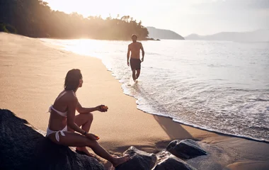 Casal desfrutando um por do sol na praia de Rio das Pedras.