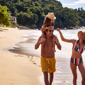 casal com filha caminhando na praia