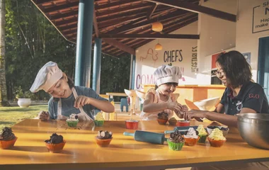 Duas crianças em aula de culinária no Mini Club, ambas usam chapéu de chef