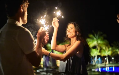 Casal segurando velas em uma festa.