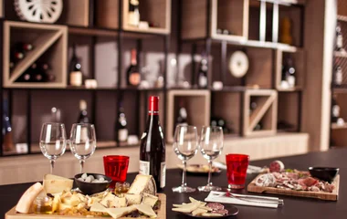 Tábuas de queijo e acompanhamentos ao lado de garrafas de vinho.
