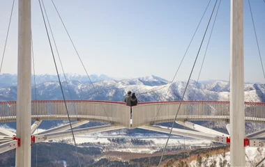 Casal se aconchega um ao outro no alto dos alpes e observa a paisagem de neve