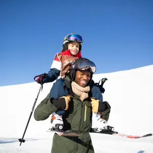 Pai carregando o filho nos ombros em paisagem de neve.