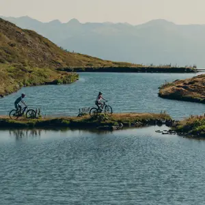 Duas pessoas pedalando próximo a um lago.