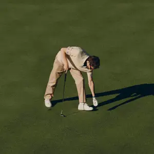 Homem em campo de golf, se preparando para jogar