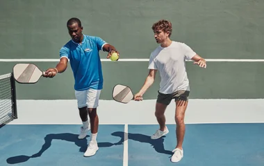 Instrutor dando aula de tennis de quadra para um GM.