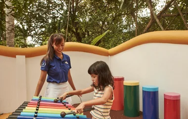 Criança brincando no playground com GO ao lado.