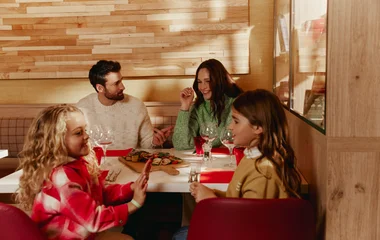 Família com mãe, pai e duas crinaças comendo juntos e conversando