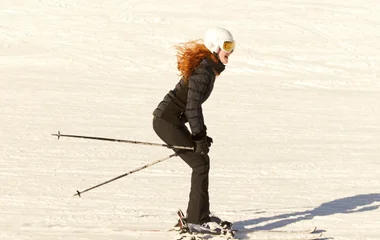 mulher com esquis descendo montanha com neve