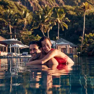 Casal na piscina do resort sorrindo.