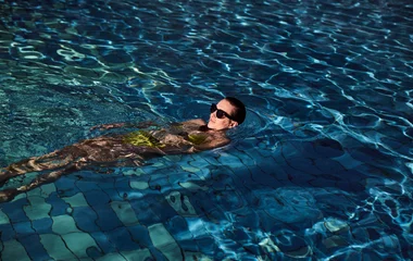 mulher em piscina de óculos escuro