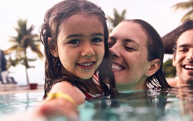 Menina no colo da mãe dentro da piscina.