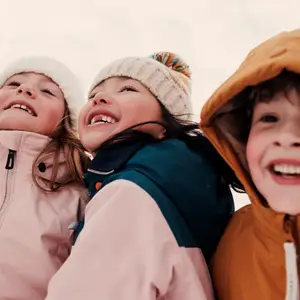 Foco em três crianças de gorro na neve.