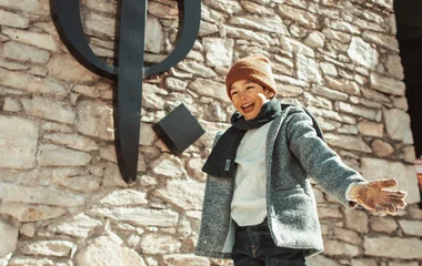 Criança feliz com trajes de frio, em frente ao resort Club Med