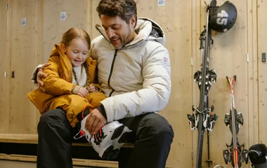 Pai e filho colocando equipamento de esqui
