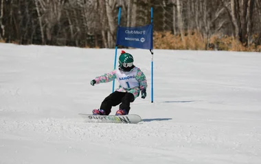 Criança praticando snowboard em resort do Club Med.