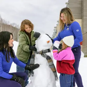 Duas crianças brincam de fazer boneco de neve junto a um GO