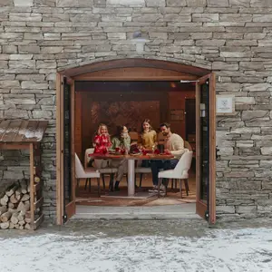 Família jantando de portas abertas, em seu chalé nos Alpes da Itália