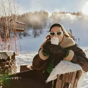 Mulher tomando bebida quente em paisagem de neve.