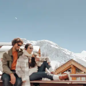 Casal sentado no resort com as montanhas ao fundo.