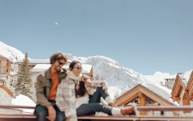 Homem e mulher sentados com neve no fundo.