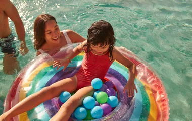 Criança na boia na piscina com a mãe