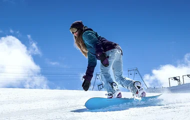 Menina praticando snowboard.