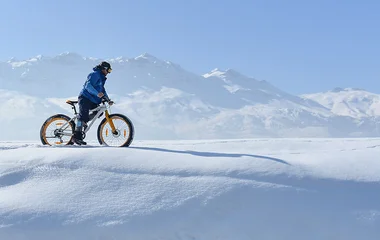 Homem andando de bicicleta na neve.